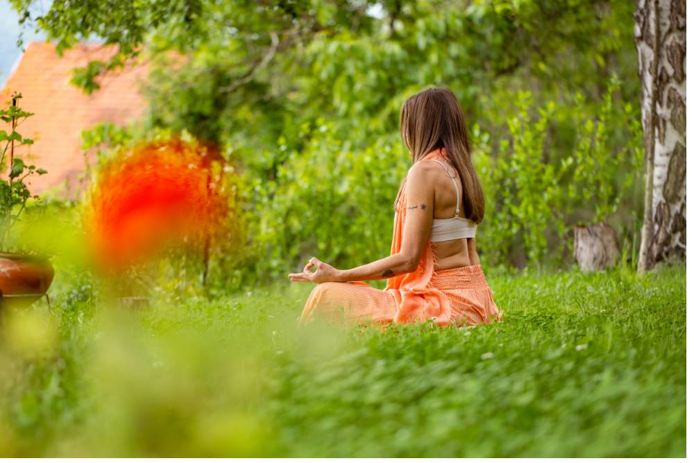 A woman meditates peacefully in a lush garden during Psilocybin Retreats in Portugal, surrounded by vibrant greenery and tranquility.