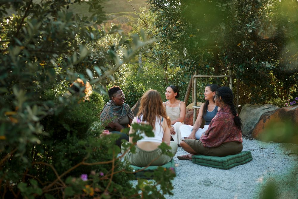 A diverse group of people gathers in a healing circle amidst nature, embodying community connection during Psilocybin Retreats in the USA.