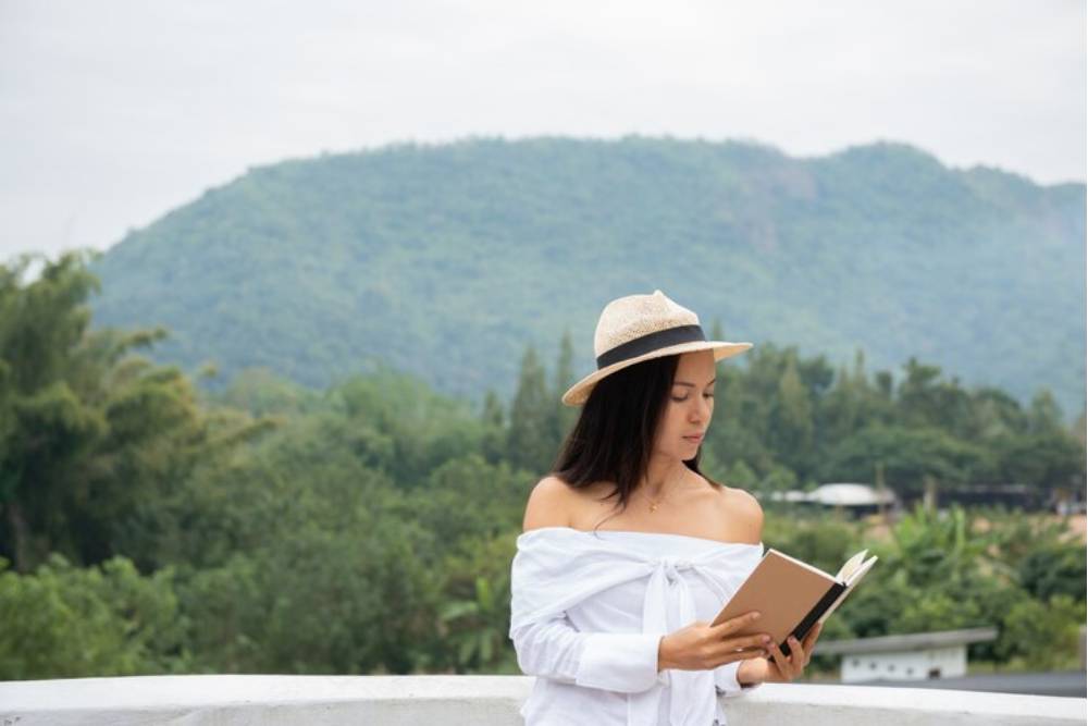 Woman reading a journal with mountain views in the background, reflecting on personal insights during San Pedro retreats in Mexico.
