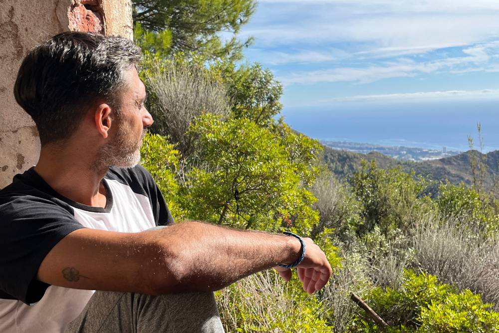 Man reflecting quietly while overlooking a scenic coastal view, embracing the introspective experience of San Pedro Retreats in Spain.