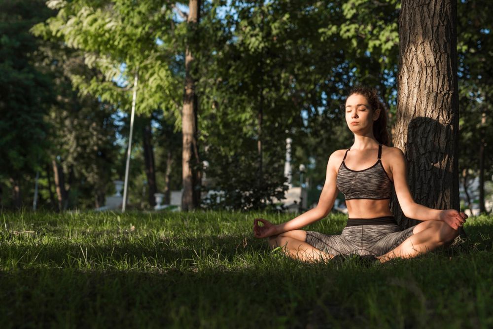 A woman practices meditation in a peaceful forest setting, embodying the serene experience of San Pedro Retreats in Portugal.