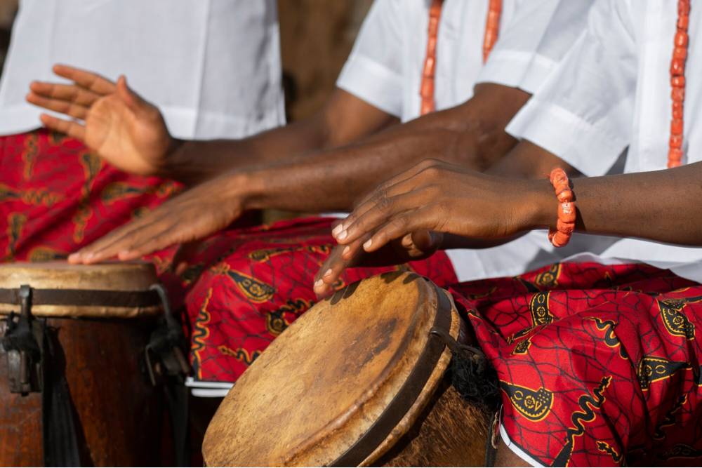 Close-up of participants rhythmically playing traditional drums during an iboga ceremony, symbolizing ancestral connection and spiritual awakening.