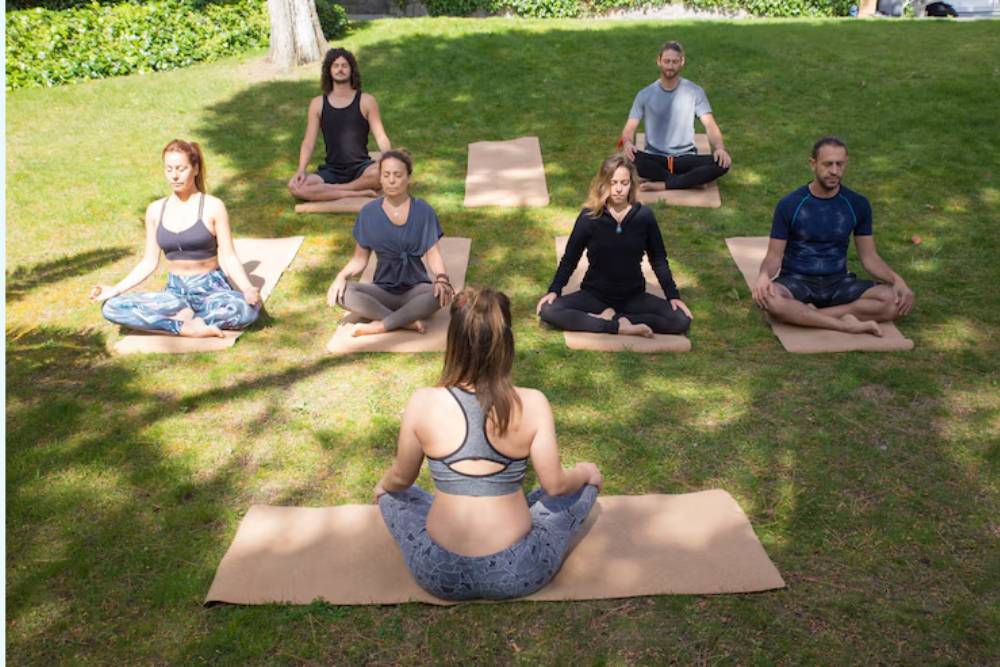 Group of people sitting in meditation on mats in a grassy area, participating in a guided session at Peyote Retreats in Costa Rica.