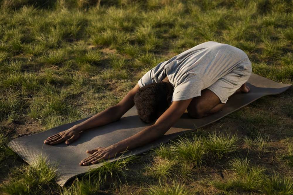 Man practicing a grounding yoga pose outdoors as part of Iboga Retreats in Gabon.