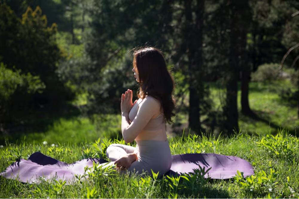 A woman meditating in a forest clearing, symbolizing inner reflection and spiritual healing, representing themes explored in iboga vs ayahuasca experiences.