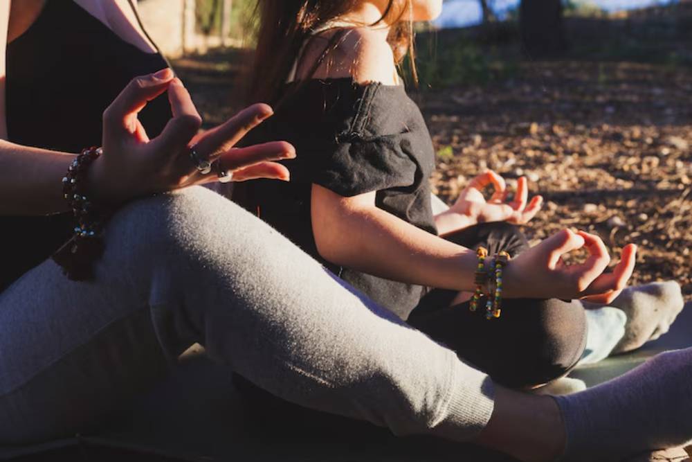Close-up of two individuals in meditation with hands in mudra pose during an outdoor Peyote Retreat in Peru.